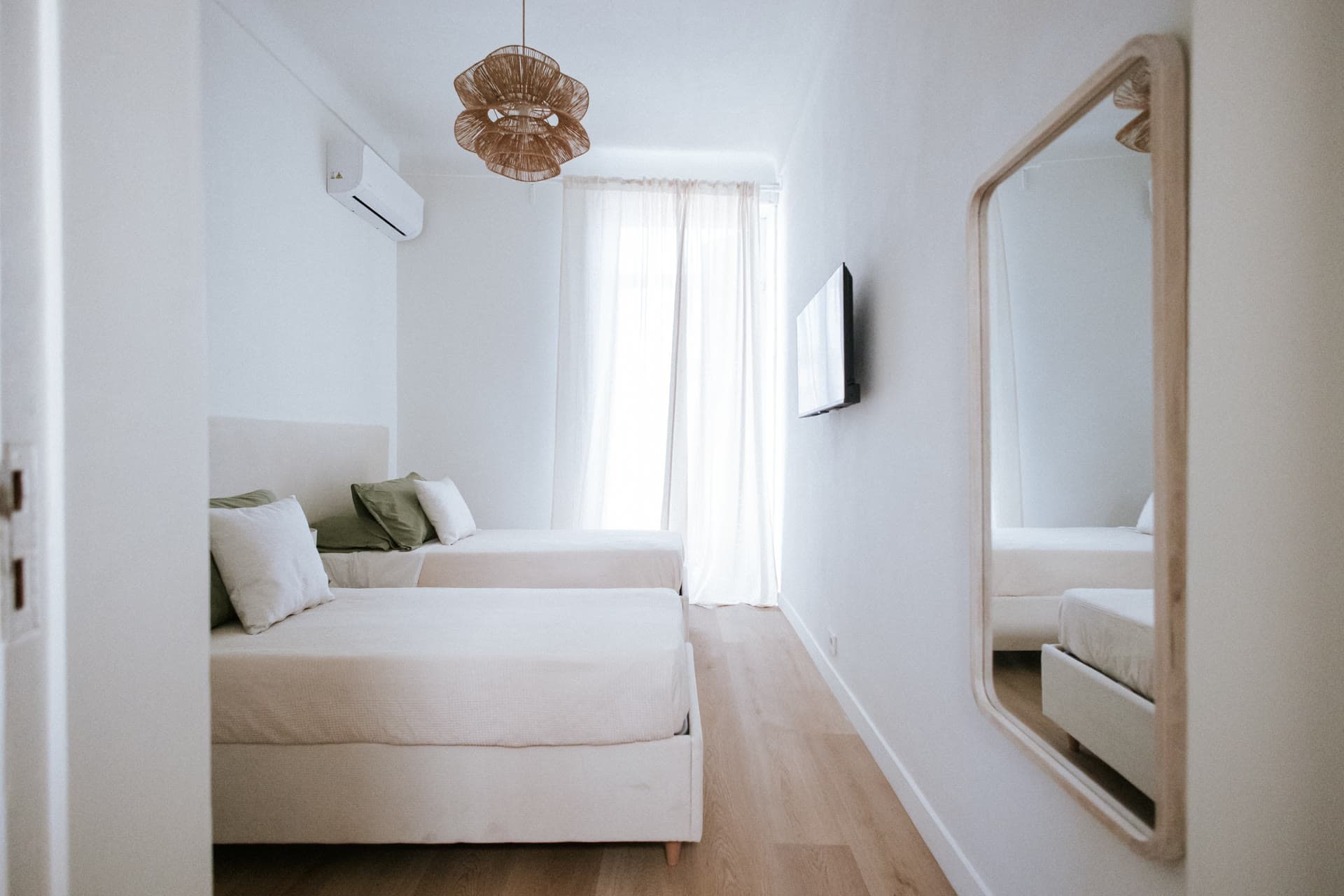 The twin bedroom with a full-length mirror and rattan pendant